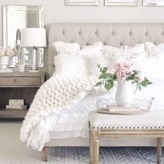 a white bed with pillows and flowers on it