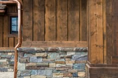 a fire hydrant sitting next to a stone wall and wooden siding on a building