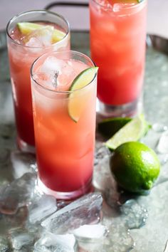 two glasses filled with drinks sitting on top of ice