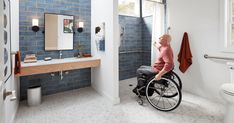 a man in a wheel chair is looking out the window at his bathroom with blue tiles on the walls