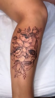 a woman's leg with a skull and flowers on it