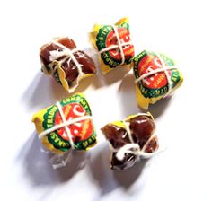 four candies wrapped in wax paper on a white surface