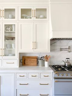 a kitchen with marble counter tops and white cabinets, gold pulls on the doors to open cupboards