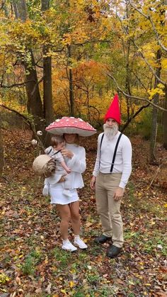 a man and woman dressed up as gnomes in the woods with an umbrella over their heads