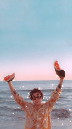 a man standing on top of a beach holding two frisbees in his hands