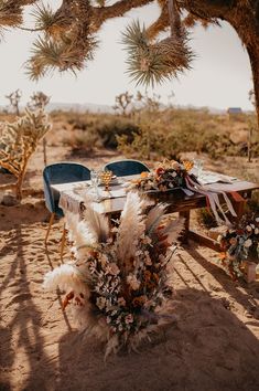 an outdoor table set up with flowers and feathers for a desert wedding in the middle of nowhere