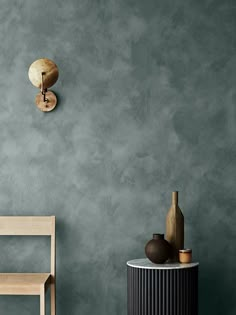 a chair and table in front of a gray wall