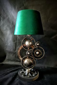 a lamp that has gears on it and a green shade over the top of it