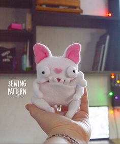 a person holding up a small stuffed animal in their hand with the words sewing pattern on it