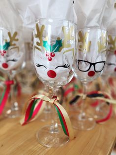 wine glasses decorated with reindeer noses and bows on a wooden countertop in front of white napkins