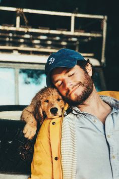 a man holding a dog in his arms while wearing a blue hat and yellow jacket