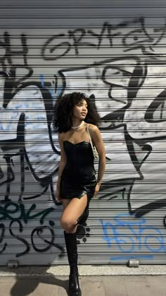 a woman standing in front of a graffiti covered wall