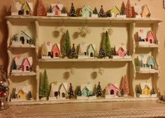 a shelf filled with lots of small christmas trees and houses on top of it's shelves