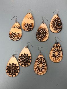 six wooden earrings with designs on them sitting next to each other in front of a gray background