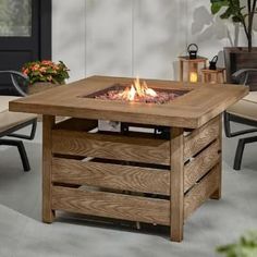 an outdoor fire pit sitting on top of a wooden table next to chairs and potted plants