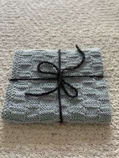 a blue knitted gift box wrapped in black string