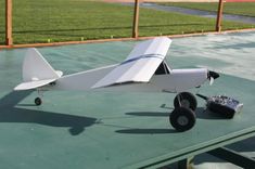 a small white airplane sitting on top of a green table next to a black box