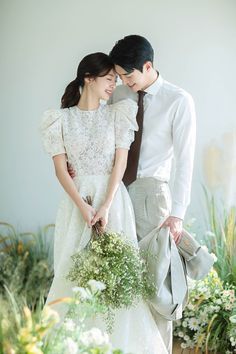 two people standing next to each other holding flowers