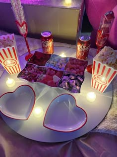 a table topped with two heart shaped plates filled with candies and popcorns on top of a white plate