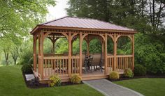 a wooden gazebo sitting on top of a lush green field