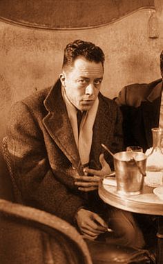 two men sitting at a table with cups and saucers