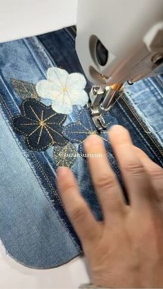 someone using a sewing machine to sew flowers on jeans