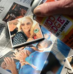 a person holding a can of soda in their hand next to newspaper pages with photos on them