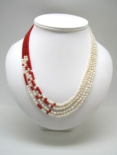 a white mannequin with red and white pearls on it's neckline