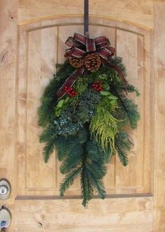 a door with a wreath and pine cones hanging on it's front door handle