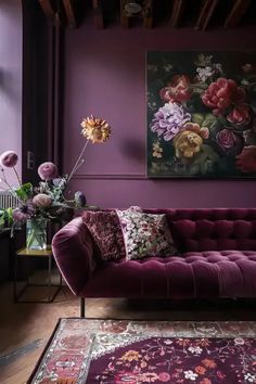 a living room with purple walls and floral decorations on the couches, rugs and coffee table