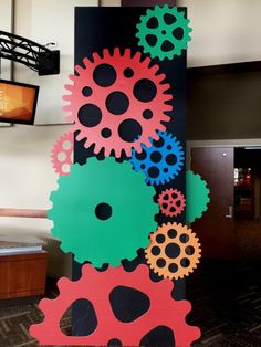 a tall clock tower with colorful gears on it's side in a lobby area