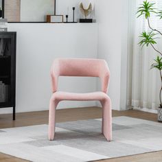 a pink chair sitting on top of a wooden floor next to a white rug in a living room