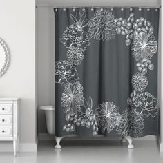 a shower curtain with flowers on it in a white and gray bathroom, next to a mirror