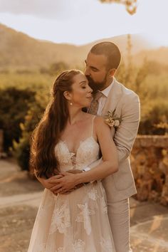 a bride and groom embracing each other outside