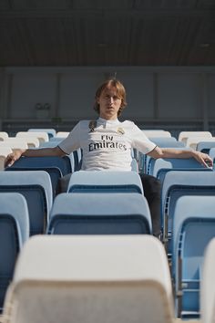 a man is sitting in the middle of rows of blue chairs with his arms outstretched