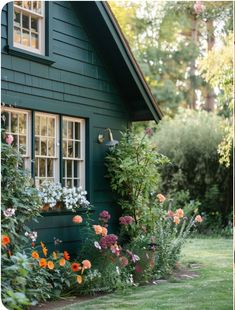 a green house with lots of flowers in the front yard