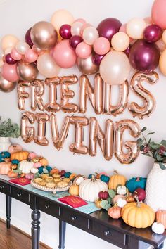 a table topped with balloons and desserts next to a sign that says friends giving