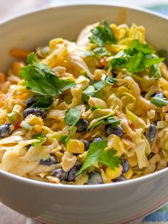 a white bowl filled with pasta salad and garnished with cilantro