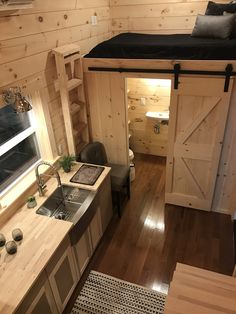 the interior of a tiny house with wood floors and walls, including a loft bed