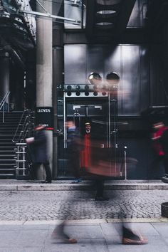 people are walking down the sidewalk in front of a building