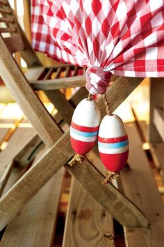 two red and white striped easter eggs hanging from a string on top of a wooden chair