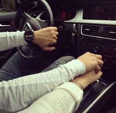 two people sitting in the driver's seat of a car with their hands on the steering wheel