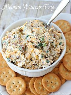 a white plate topped with crackers and a bowl filled with chicken salad next to crackers