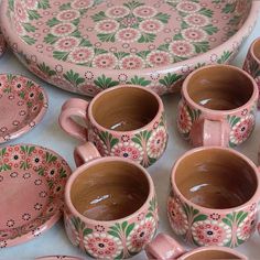 a table topped with lots of pink and green cups and saucers covered in flowers