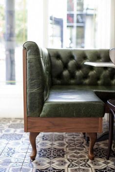 a green leather chair sitting next to a table