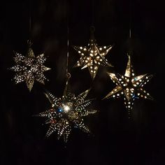 three star shaped lights hanging from strings in the dark