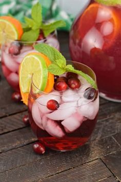 two glasses filled with drinks and garnished with fruit