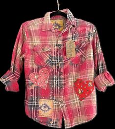 a pink plaid shirt with hearts on the chest and collar, hanging from a hanger