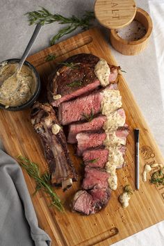 sliced steak on a cutting board with garlic and herbs next to it, ready to be served