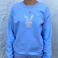 a person wearing a blue sweatshirt with a bunny head on the front and back, standing in front of a white wall